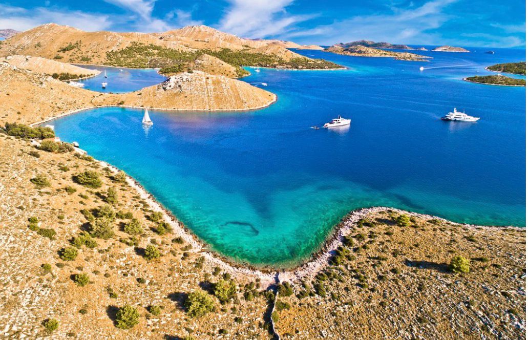 Kornati stone ridge dropping into a turquoise cove
