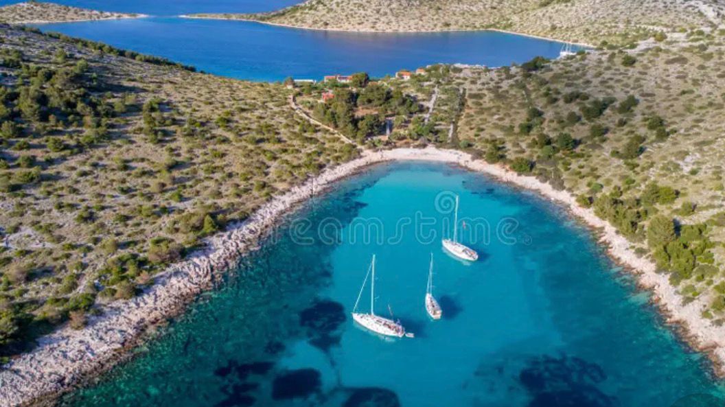 Three sailboats anchored in a quiet Kornati bay